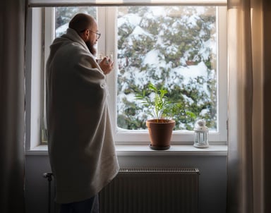 Un homme a froid devant sa fenêtre