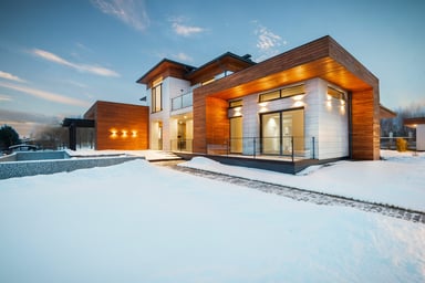 Maison contemporaine éclairée sous la neige illustrant la consommation d'électricité en hiver