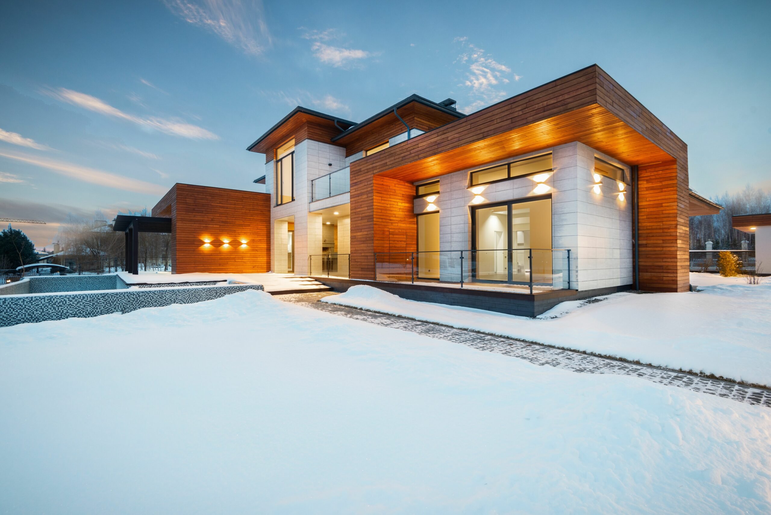 Maison contemporaine éclairée sous la neige illustrant la consommation d'électricité en hiver
