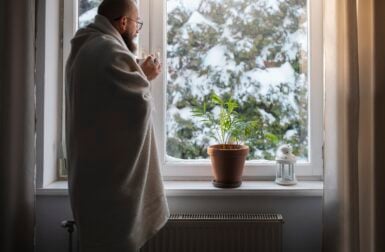 Un homme a froid devant sa fenêtre